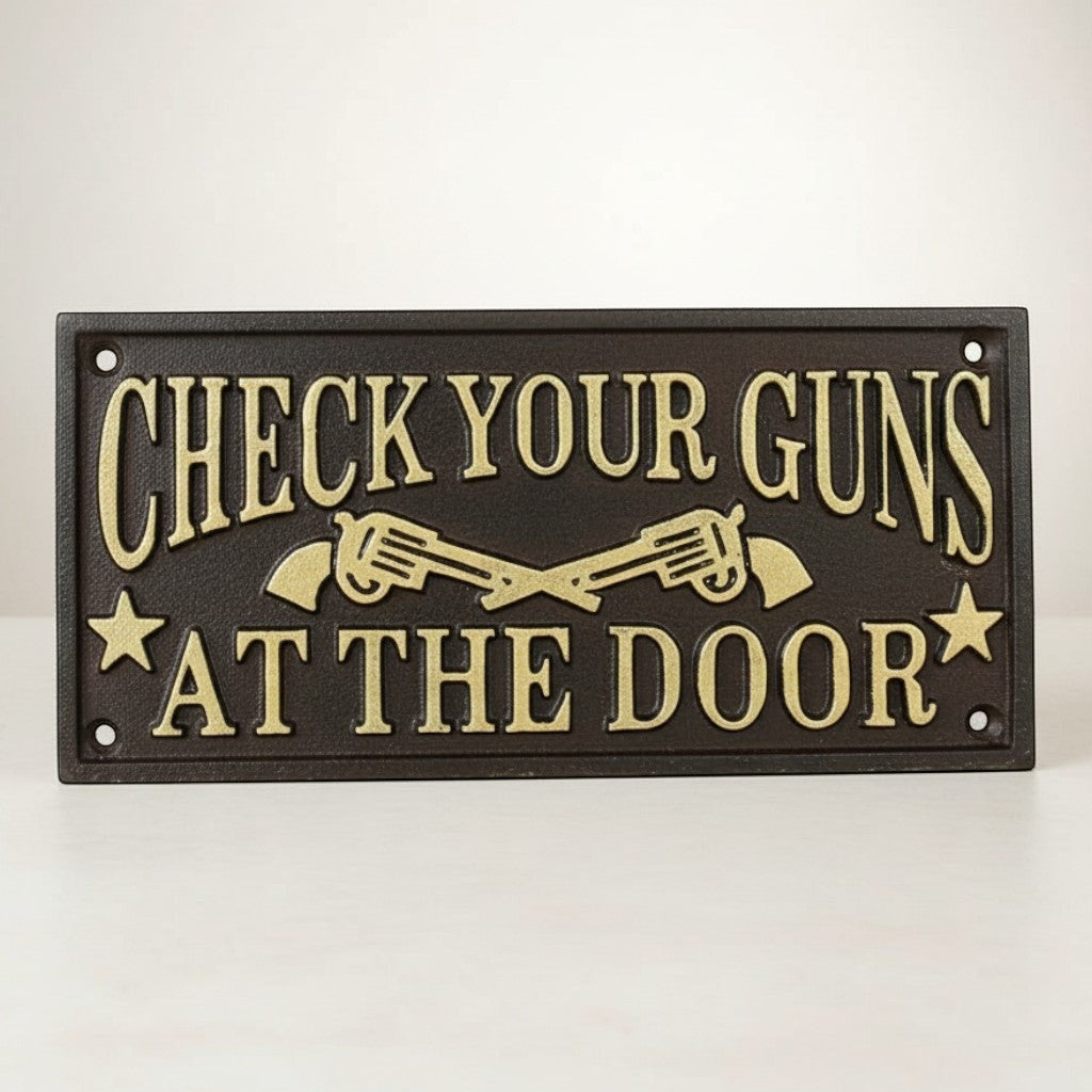 Jones Peak cast iron wall plaque with raised gold lettering reading "CHECK YOUR GUNS AT THE DOOR" and crossed revolvers.